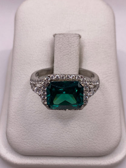 Anillo solitario de plata con circonia verde esmeralda en la mano de una mujer