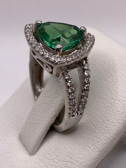 Anillo colocado en dedo femenino, circonia verde captando luz con intensidad diamantina