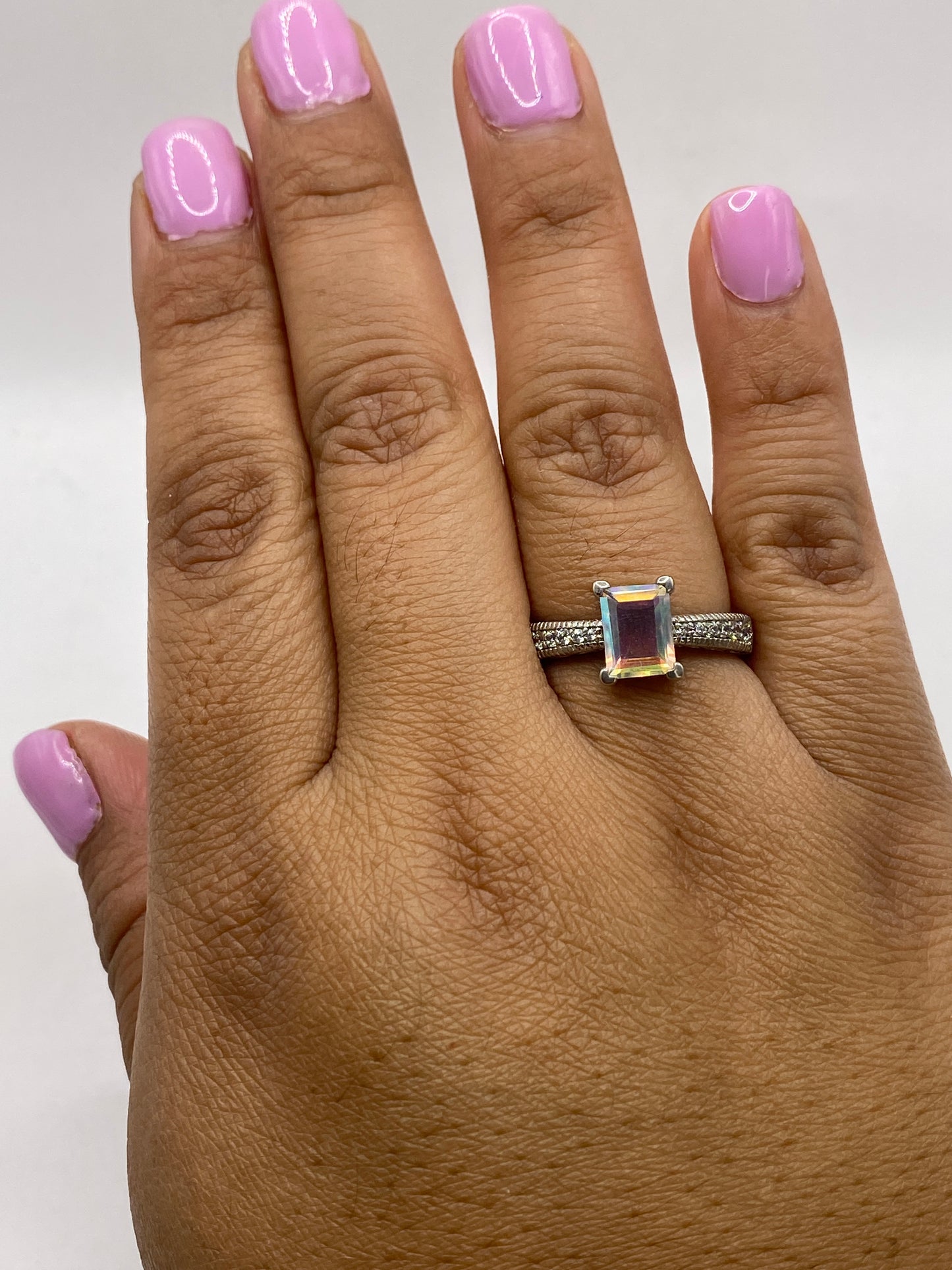 Anillo solitario circonia multicolor en dedo femenino con esmalte rosa