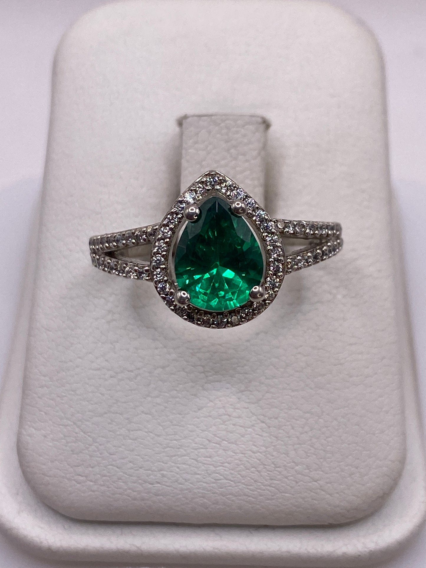 Anillo de plata solitario con circonia verde en corte pera, exhibido en blanco