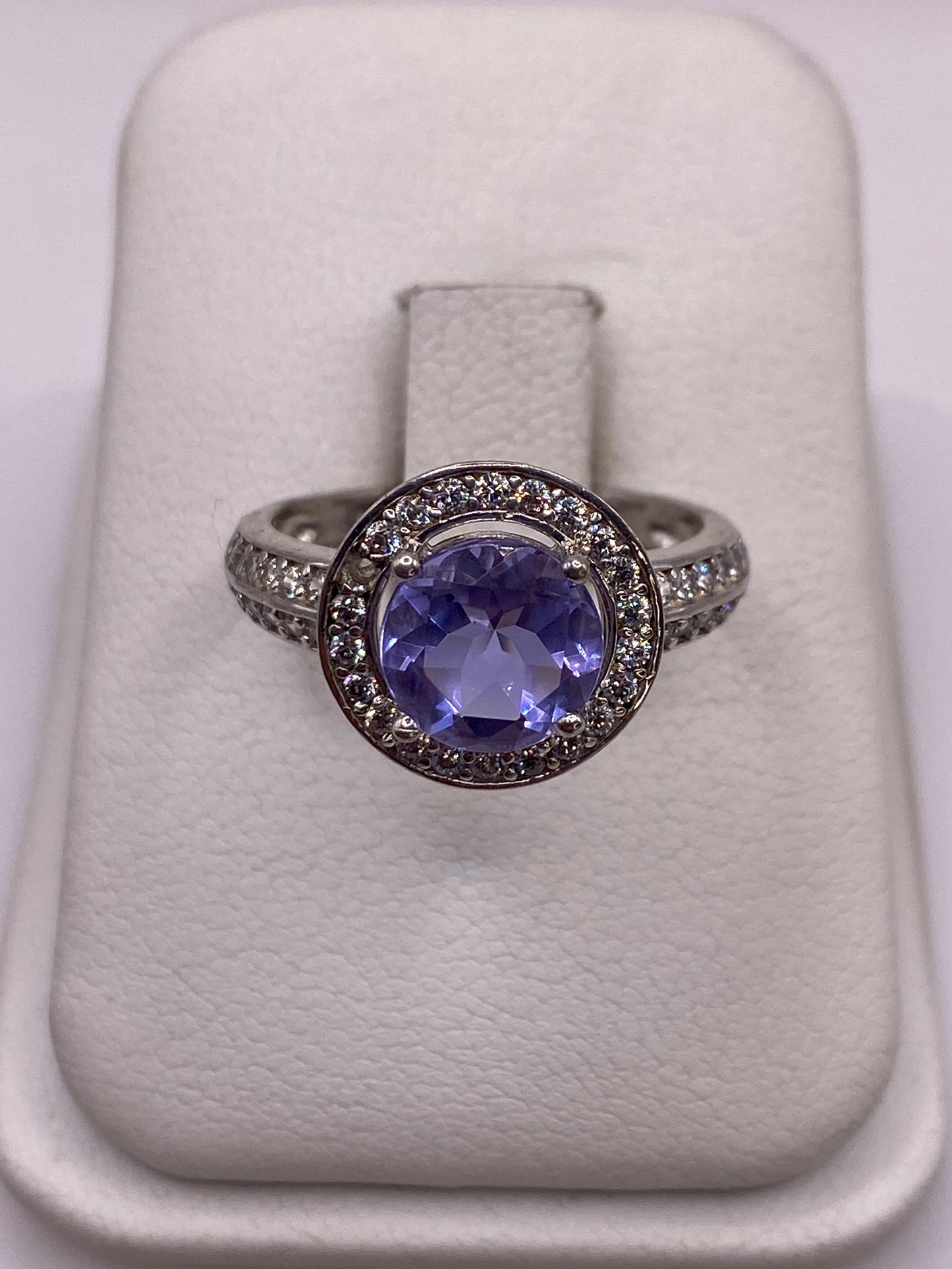 Anillo de plata solitario con circonia morada en mano de mujer con esmalte rosa