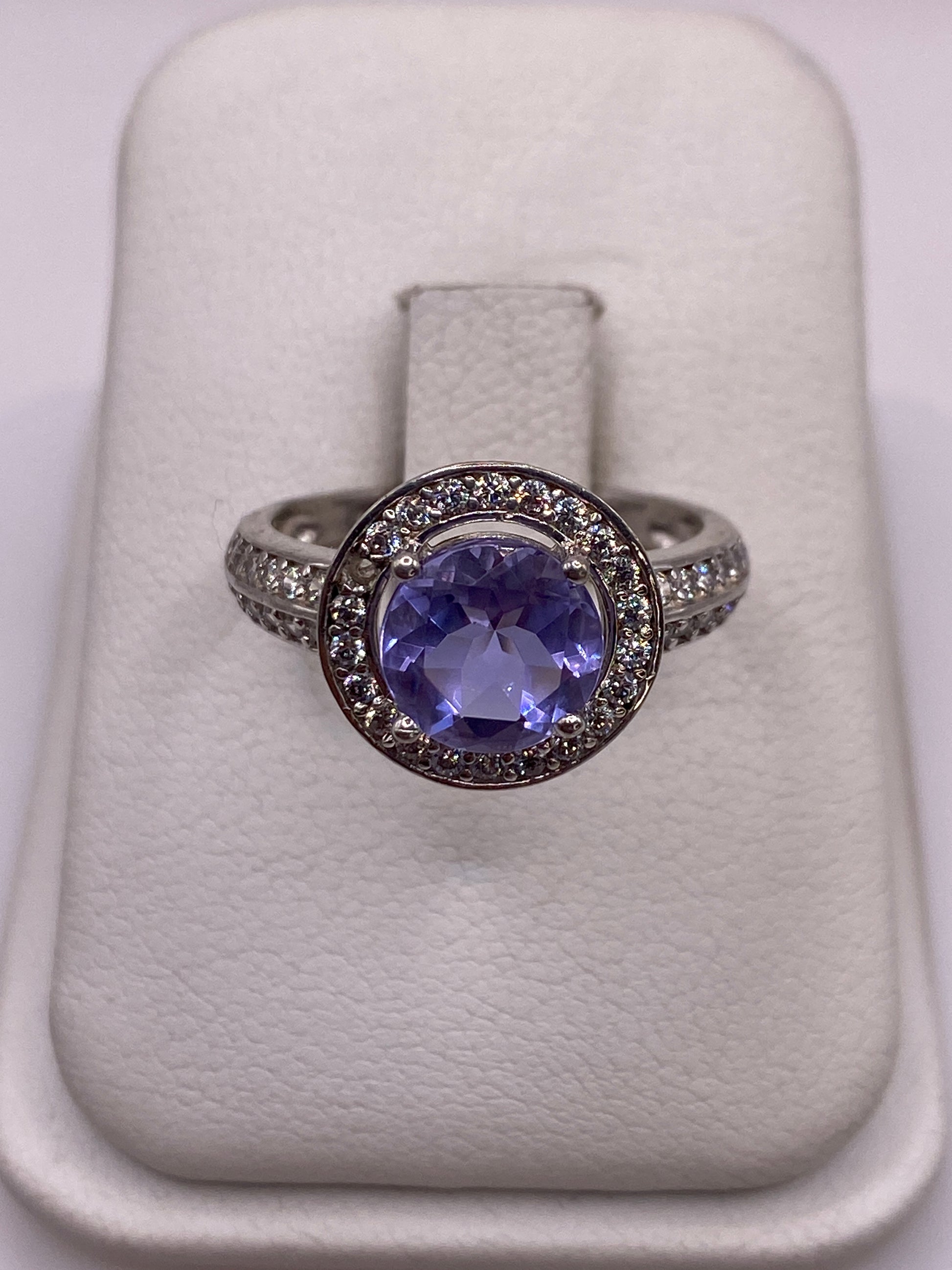 Anillo de plata solitario con circonia morada en mano de mujer con esmalte rosa