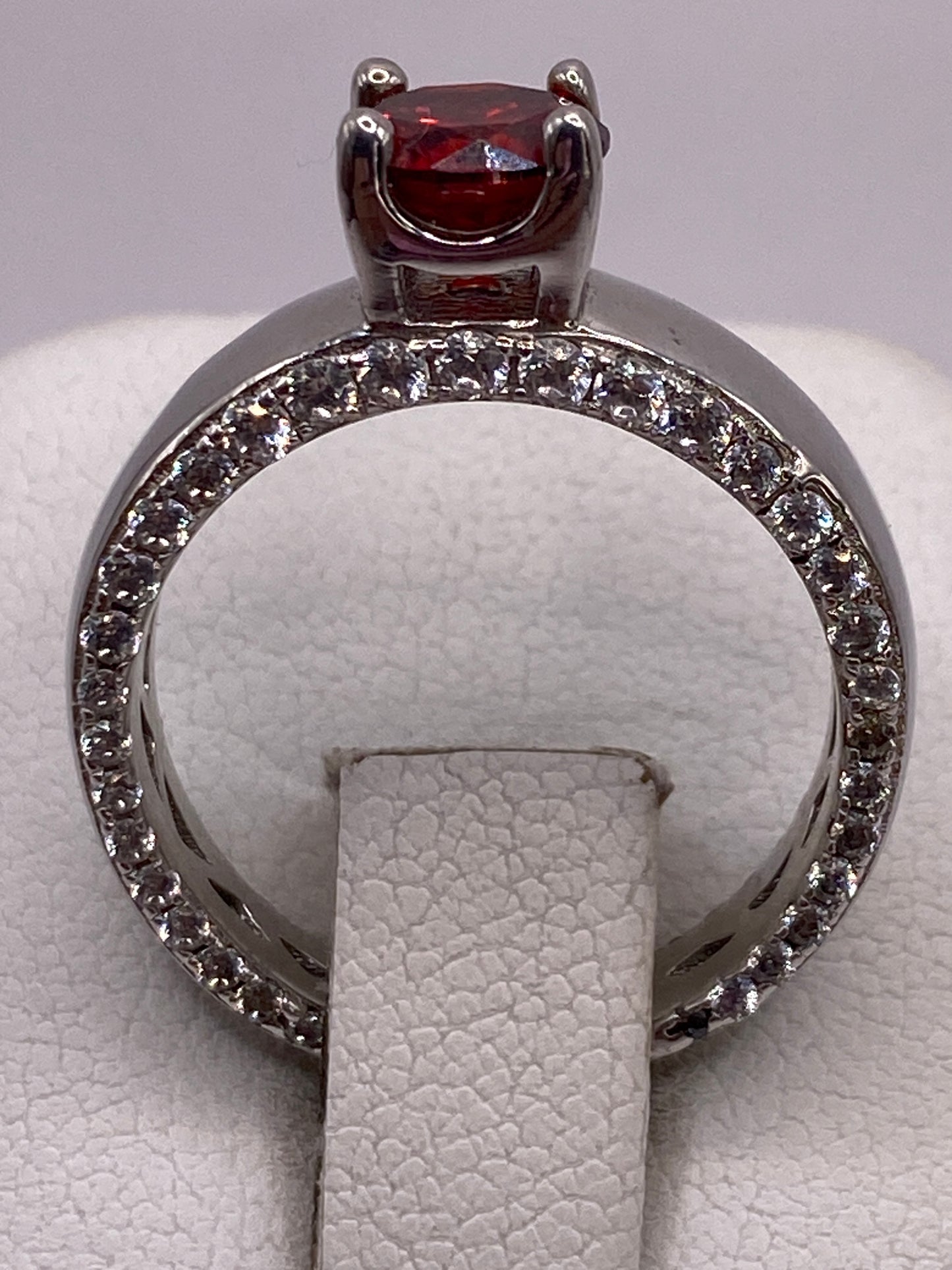 Anillo de plata solitario con circonia roja brillante en la mano de una mujer