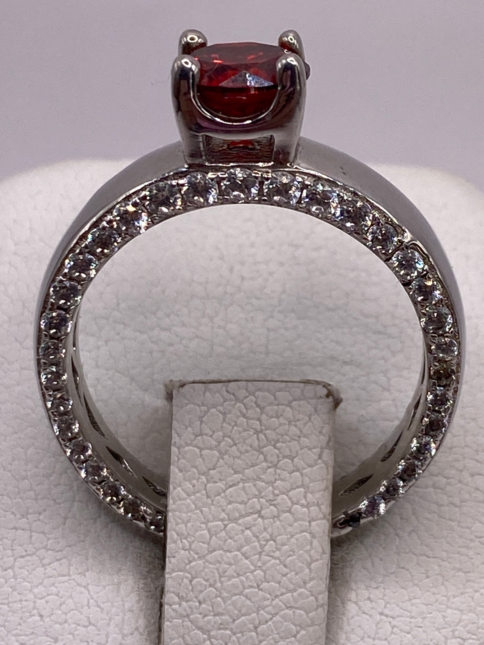 Anillo de plata solitario con circonia roja brillante en la mano de una mujer