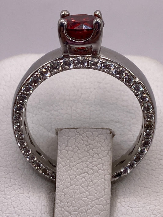 Anillo de plata solitario con circonia roja brillante en la mano de una mujer