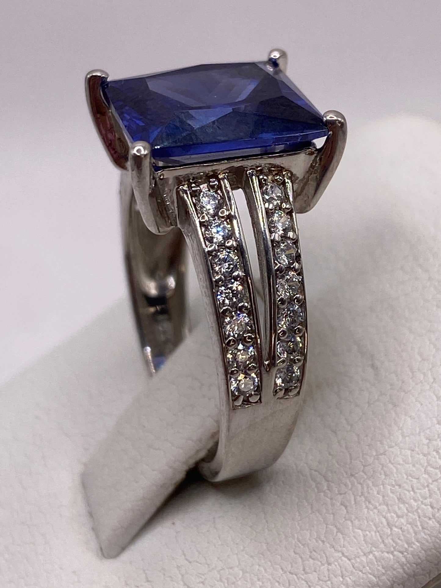 Detalle lateral del anillo con enlaces de circonias blancas flanqueando la piedra