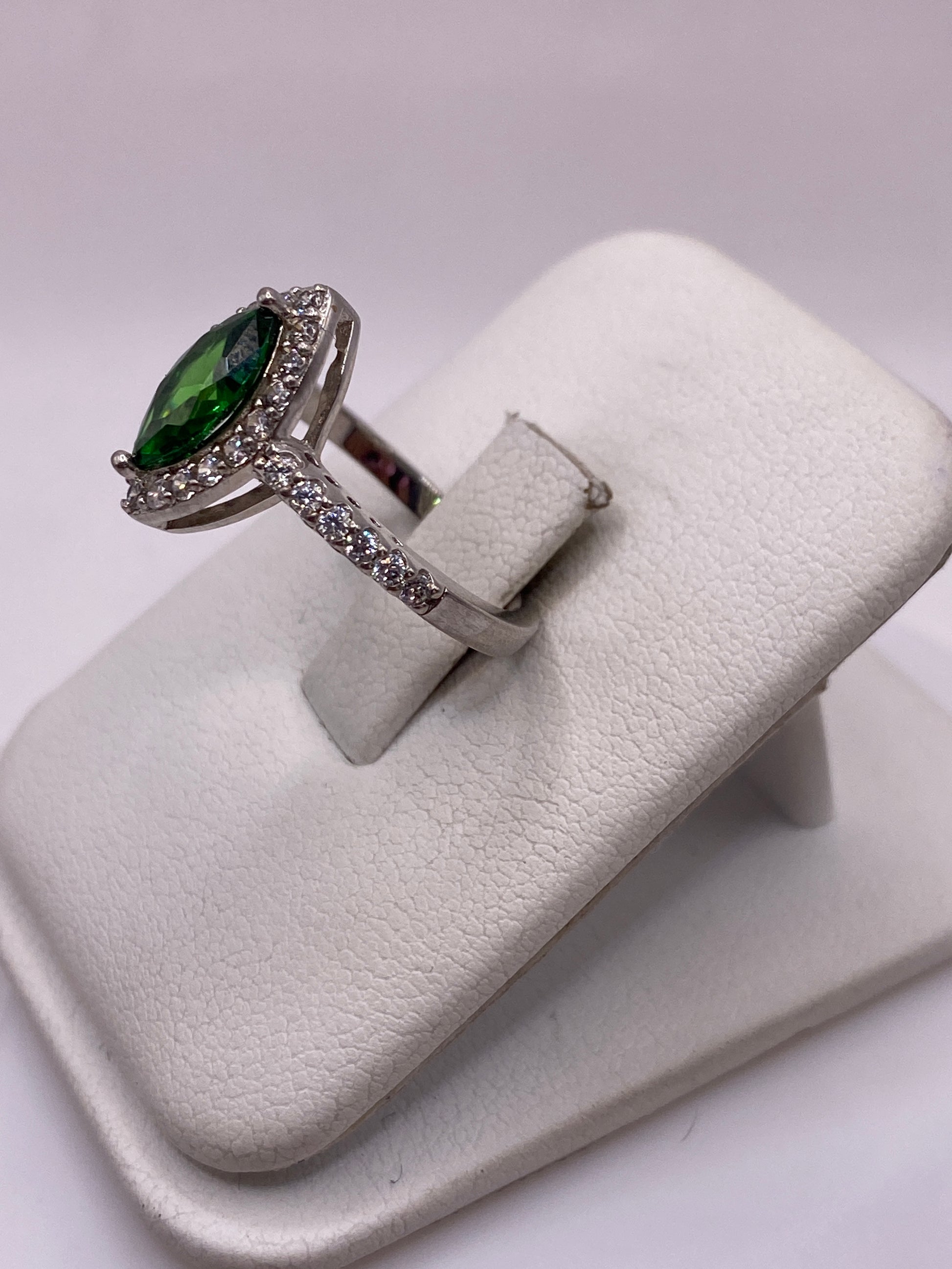 Anillo solitario verde en la mano mostrando el brillo de la piedra desde un ángulo lateral
