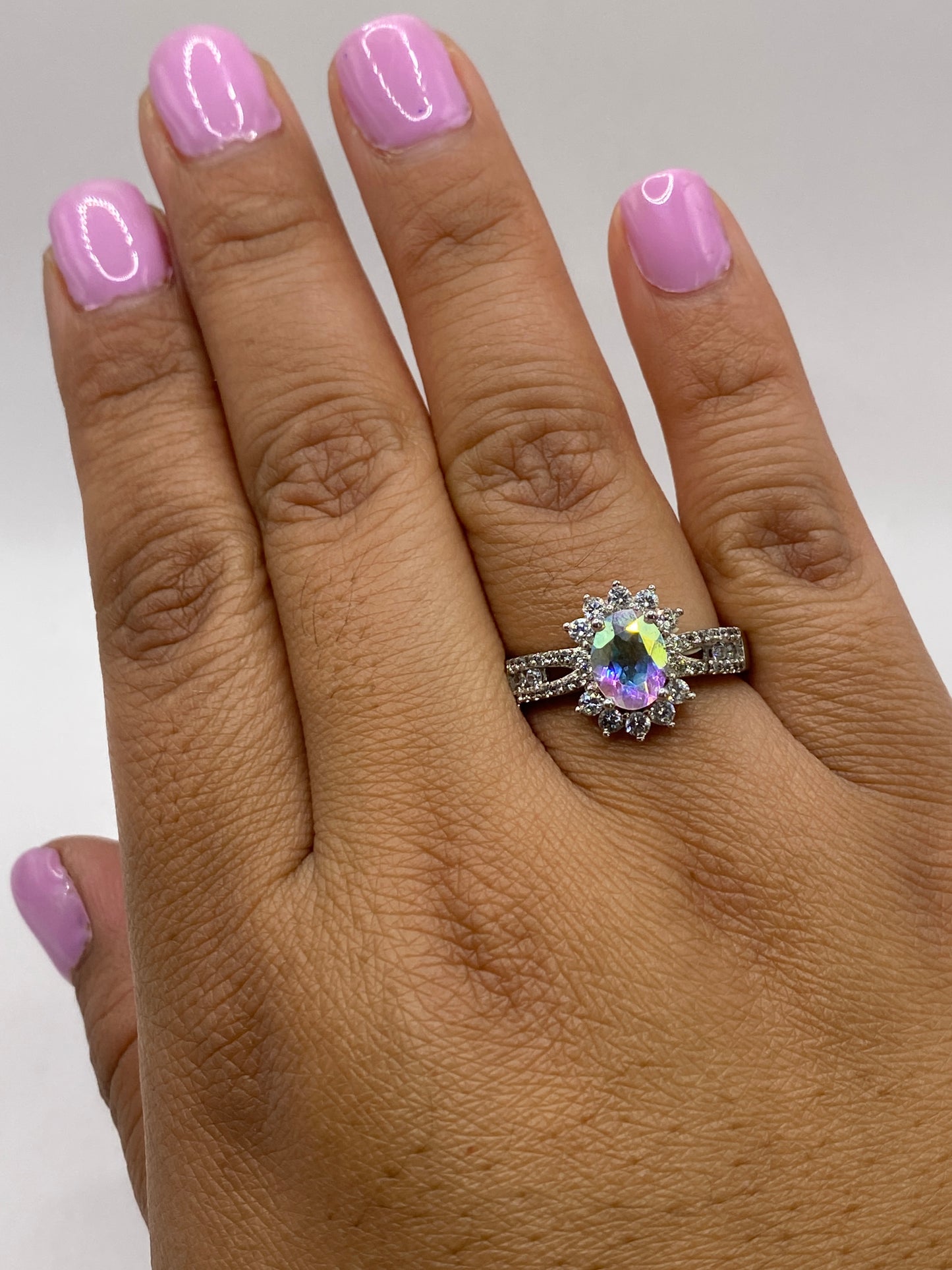 Anillo en mano de mujer con manicura mostrando el fuego multicolor de la circonia