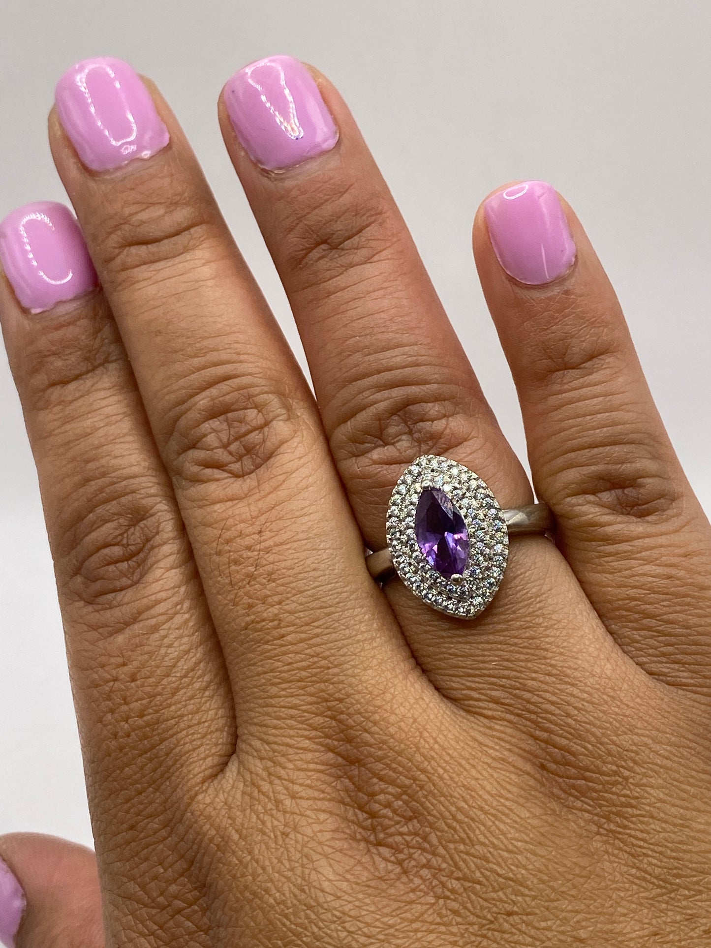 Anillo solitario puesto en dedo mostrando la circonia morada facetada con fuego intenso