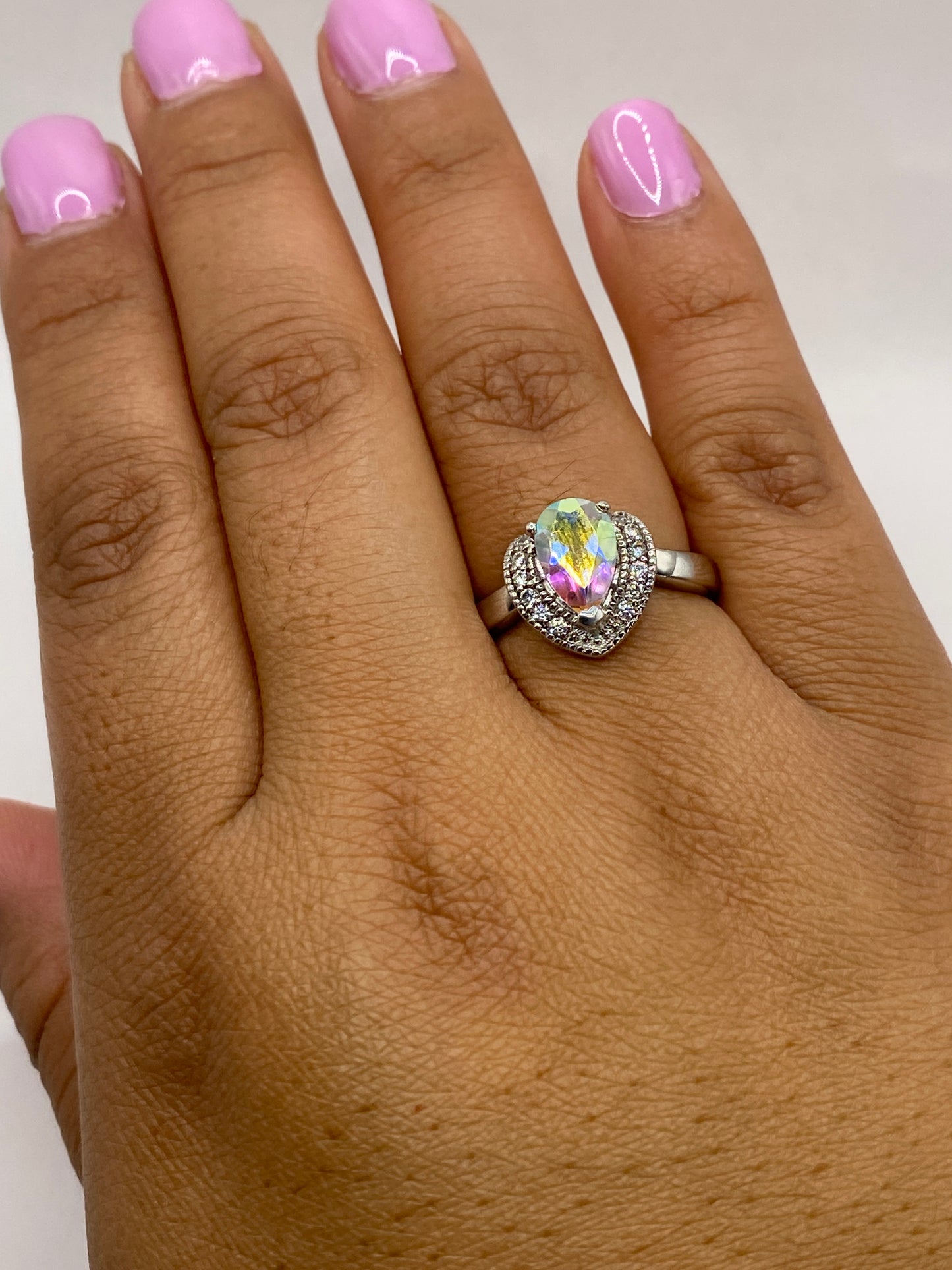 Anillo solitario en plata puesta en dedo, mostrando el fuego de la piedra
