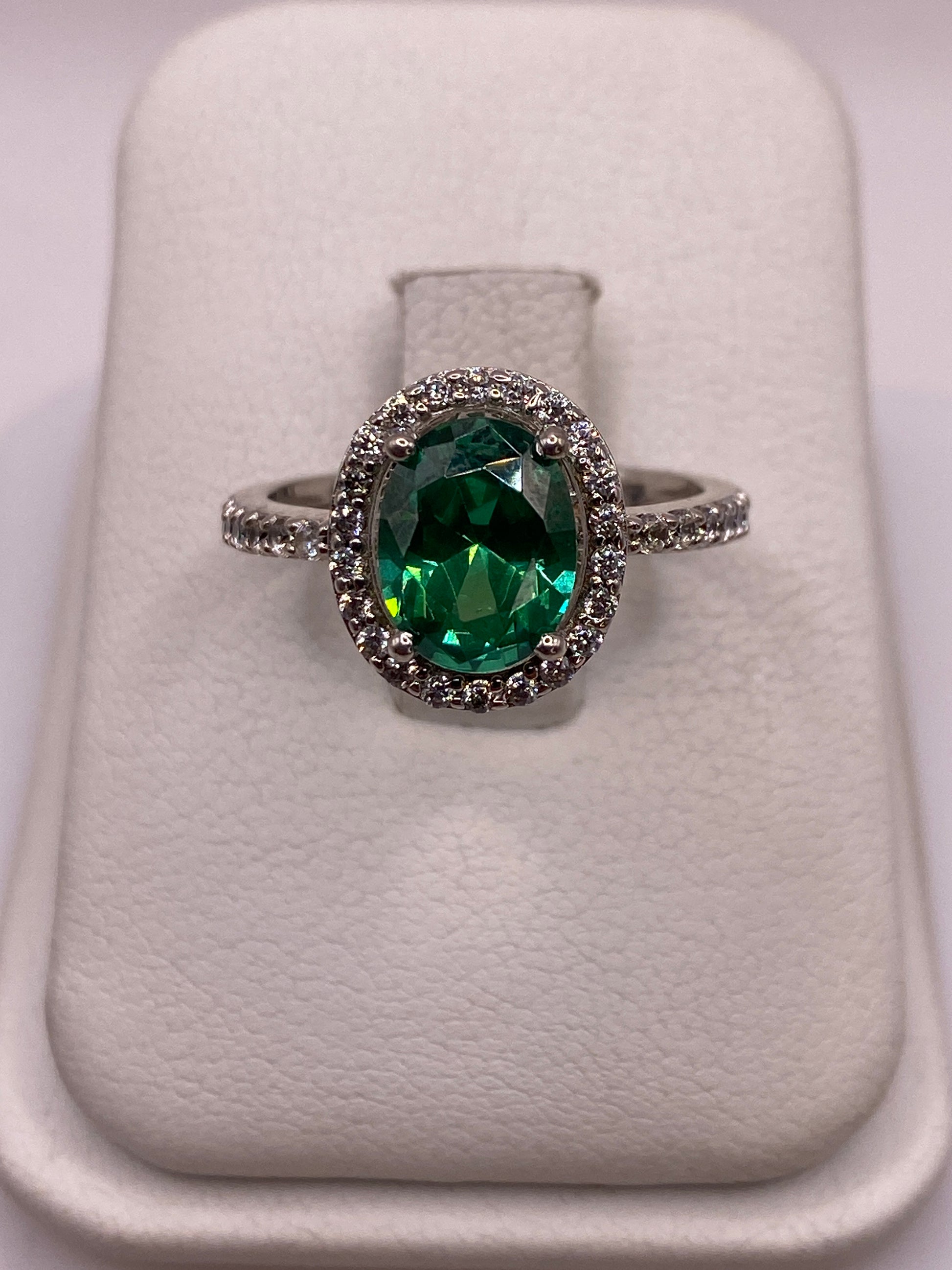 Anillo de plata solitario con circonia verde esmeralda en la mano de una mujer