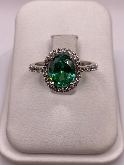 Anillo de plata solitario con circonia verde esmeralda en la mano de una mujer