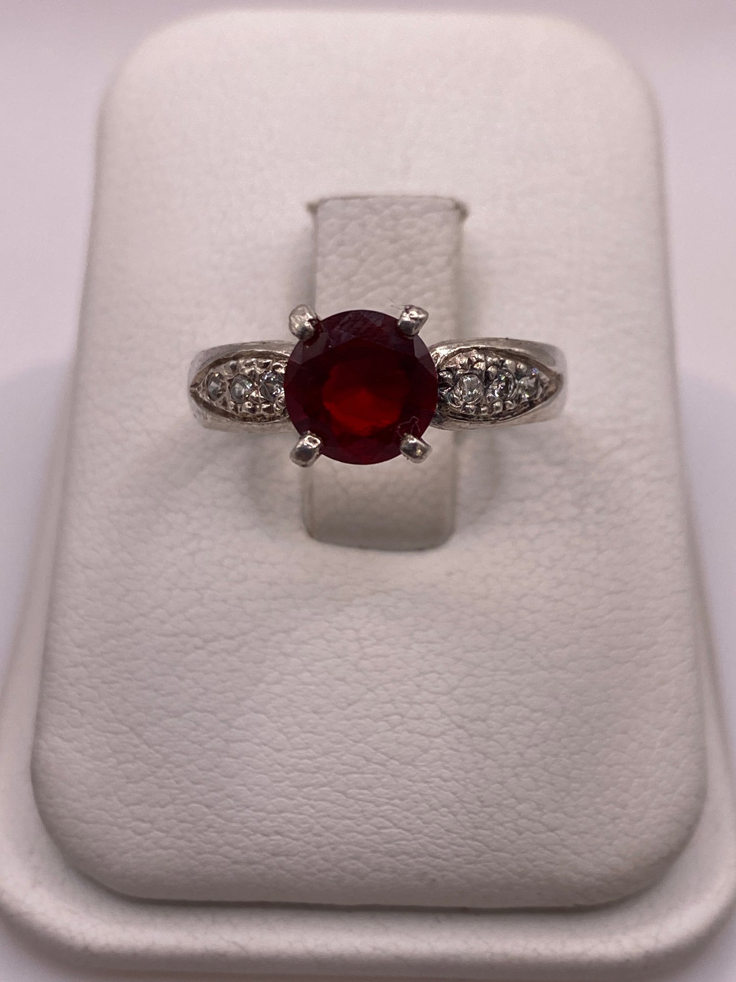 Anillo solitario de plata con circonia roja tono rubí en estuche blanco, frente