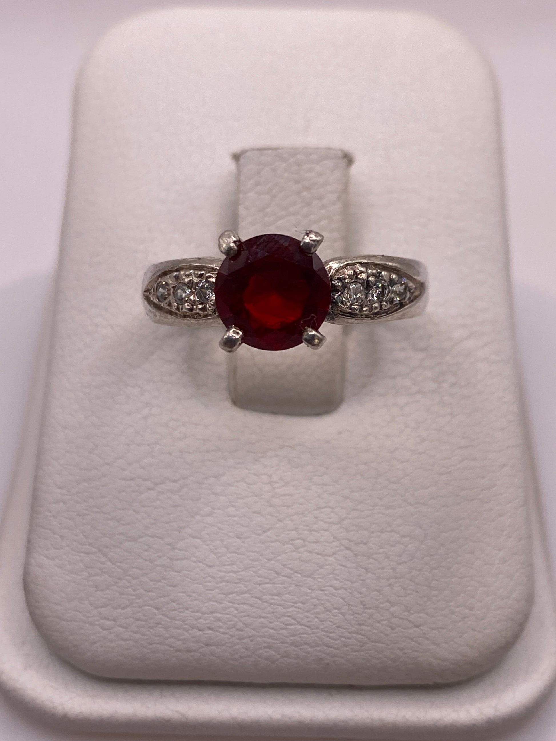 Anillo solitario de plata con circonia roja tono rubí en estuche blanco, frente