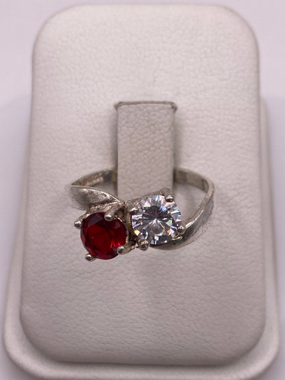 Anillo de plata con circonia roja brillante y piedra blanca, vista frontal en estuche blanco