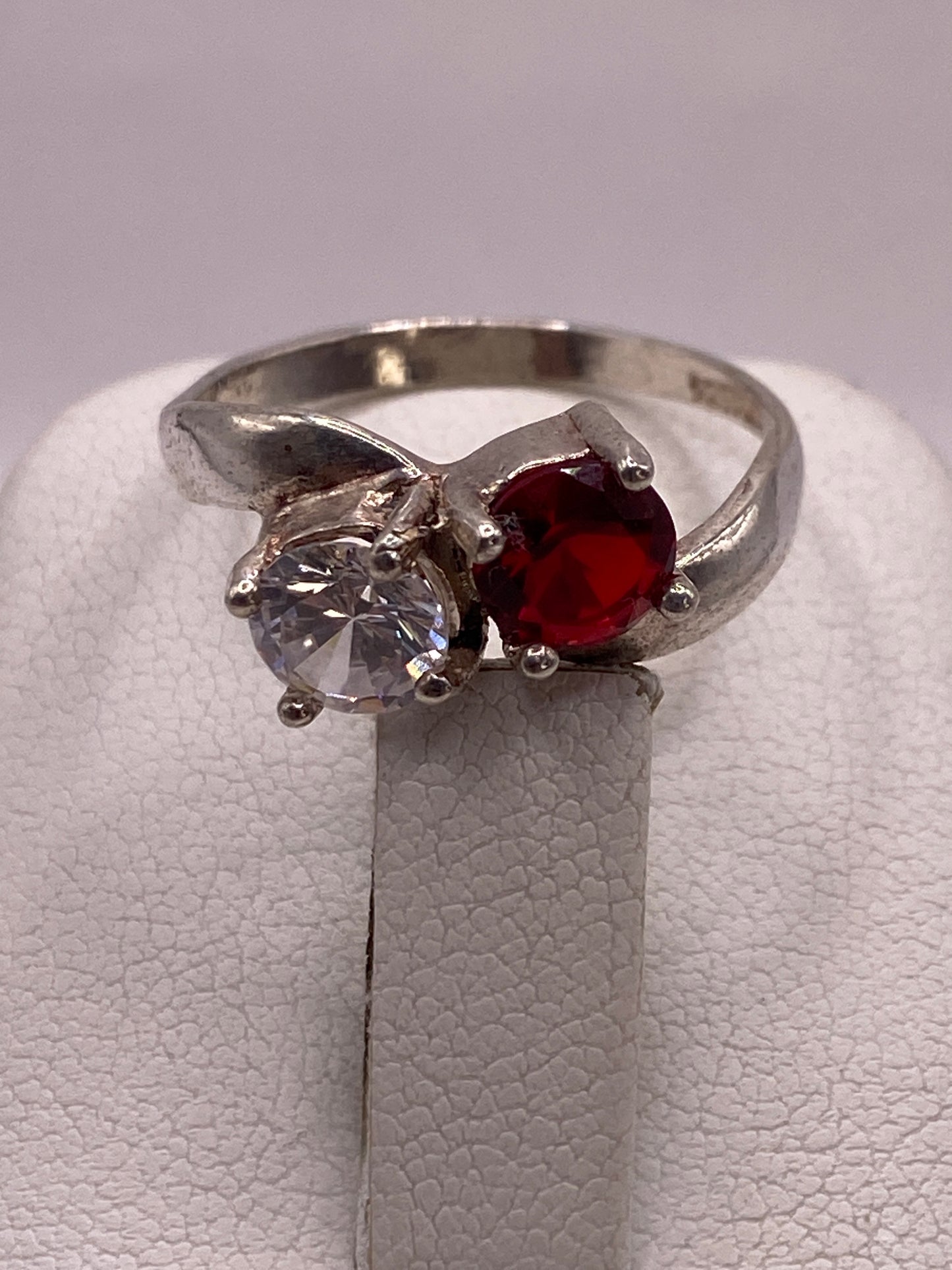 Anillo de plata coctel con circonia roja en mano con uñas rosa lavanda