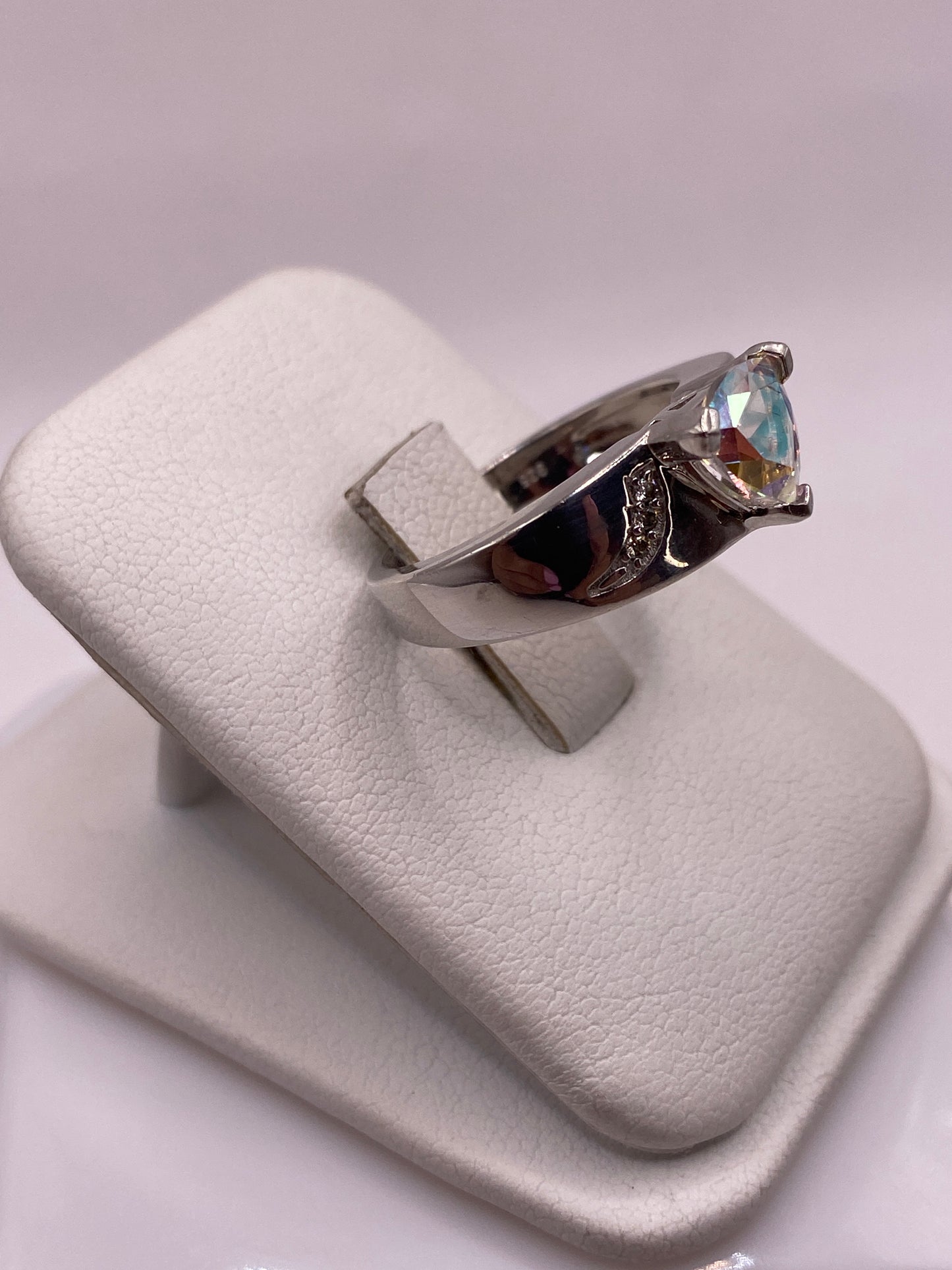 Vista frontal del anillo mostrando la circonia facetada con reflejos azules, dorados y violetas