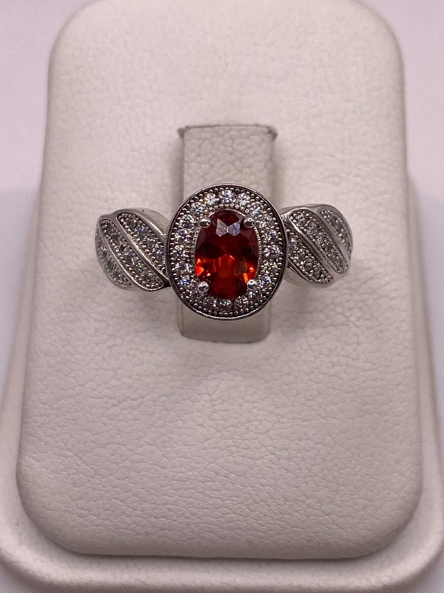 Anillo de plata solitario con circonia naranja facetada y alas decoradas, vista frontal en estuche