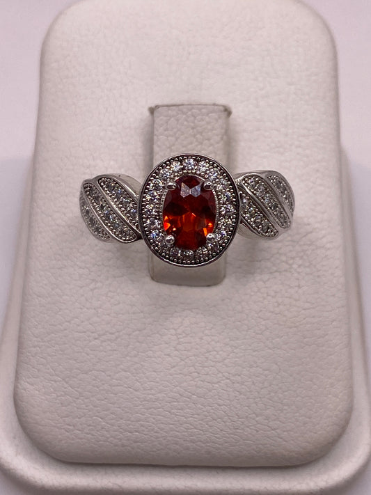 Anillo de plata solitario con circonia naranja facetada y alas decoradas, vista frontal en estuche