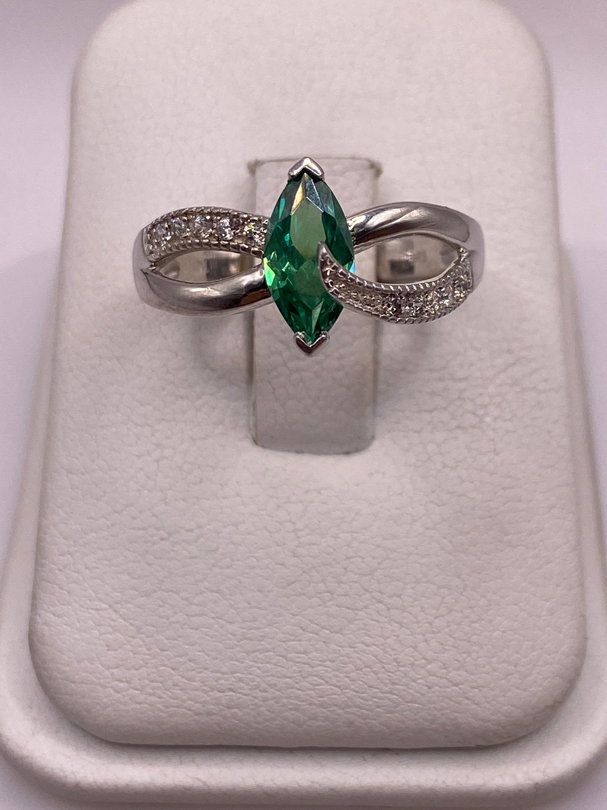 Anillo de plata solitario con circonia verde facetada, brazos ondulantes, en la mano de una mujer