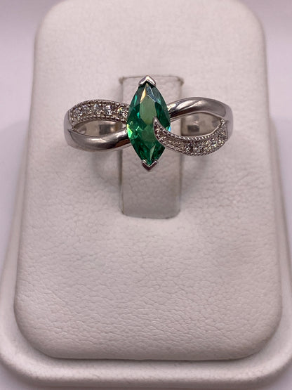 Anillo de plata solitario con circonia verde facetada, brazos ondulantes, en la mano de una mujer