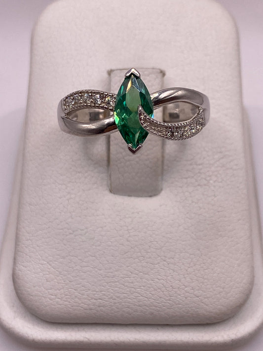 Anillo de plata solitario con circonia verde facetada, brazos ondulantes, en la mano de una mujer