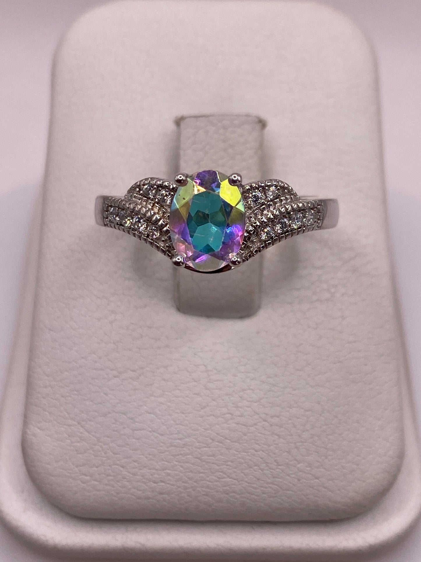 Anillo de plata con circonia multicolor en amarillo, azul y púrpura sobre almohada blanca
