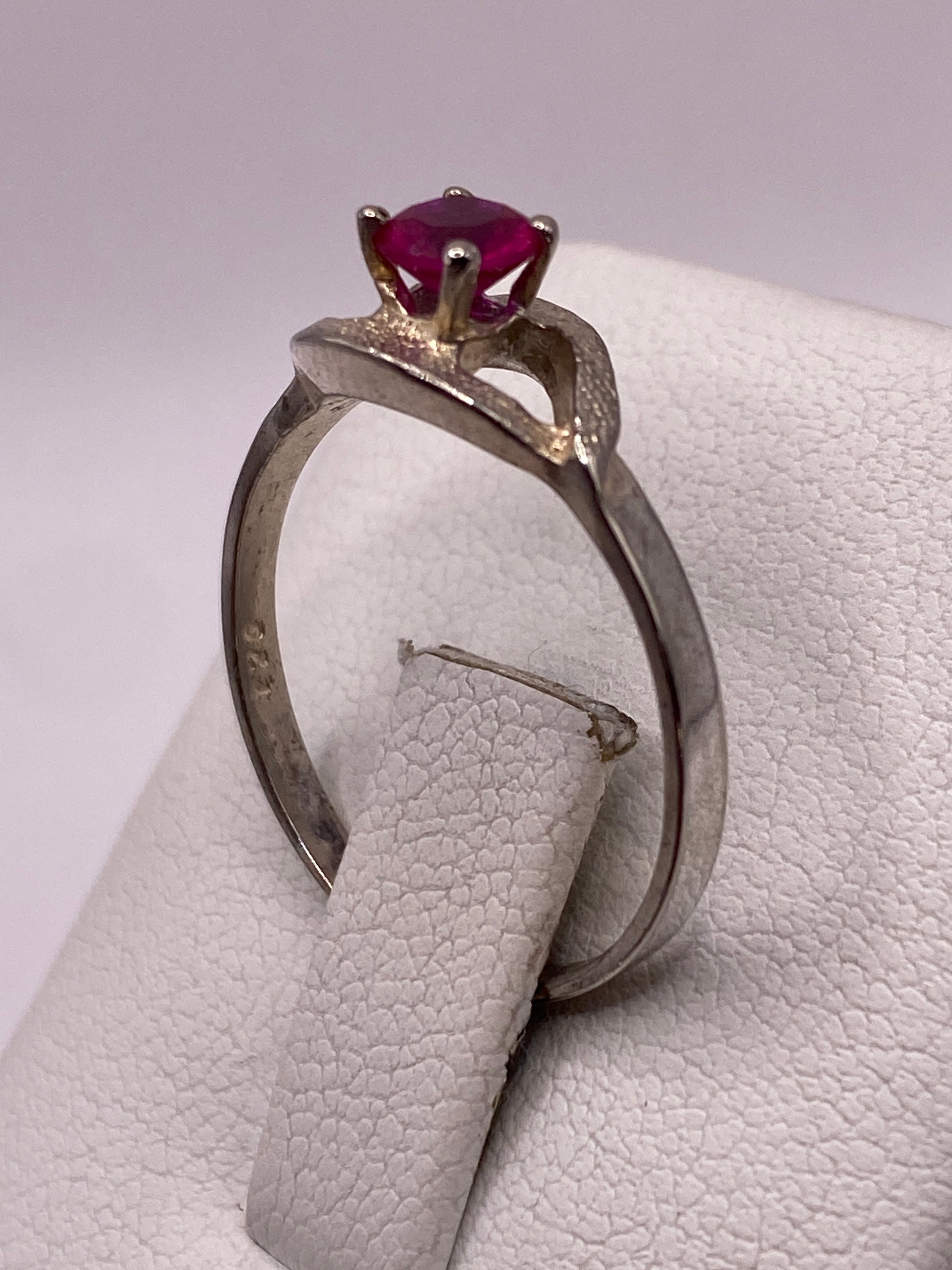 Anillo de circonia roja colocado en dedo, mostrando el brillo intenso de la piedra