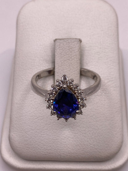 Anillo de plata solitario con circonia morada facetada y halo envolvente, sobre anillo de exhibición blanco