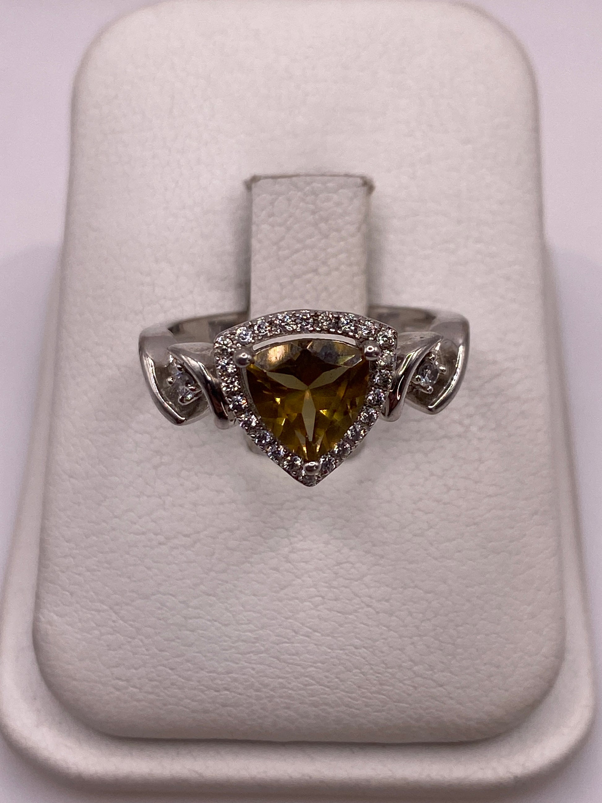 Anillo de plata solitario con circonia amarilla y alas laterales, visto desde arriba en estuche blanco