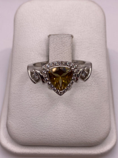 Anillo de plata solitario con circonia amarilla y alas laterales, visto desde arriba en estuche blanco