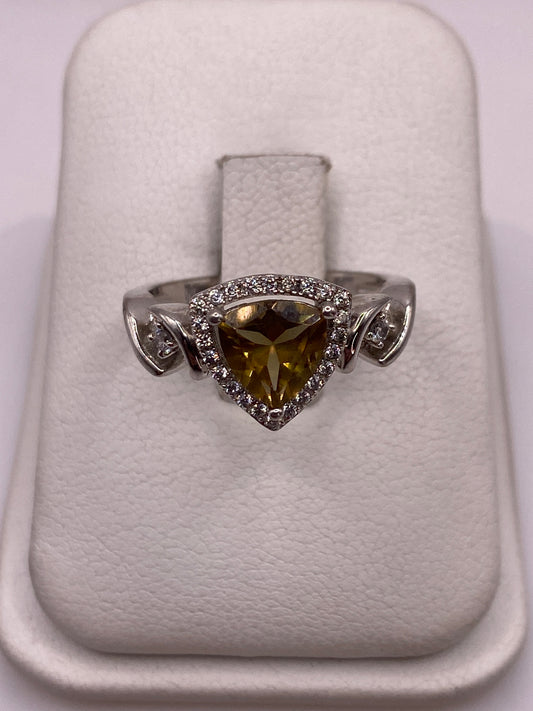 Anillo de plata solitario con circonia amarilla y alas laterales, visto desde arriba en estuche blanco