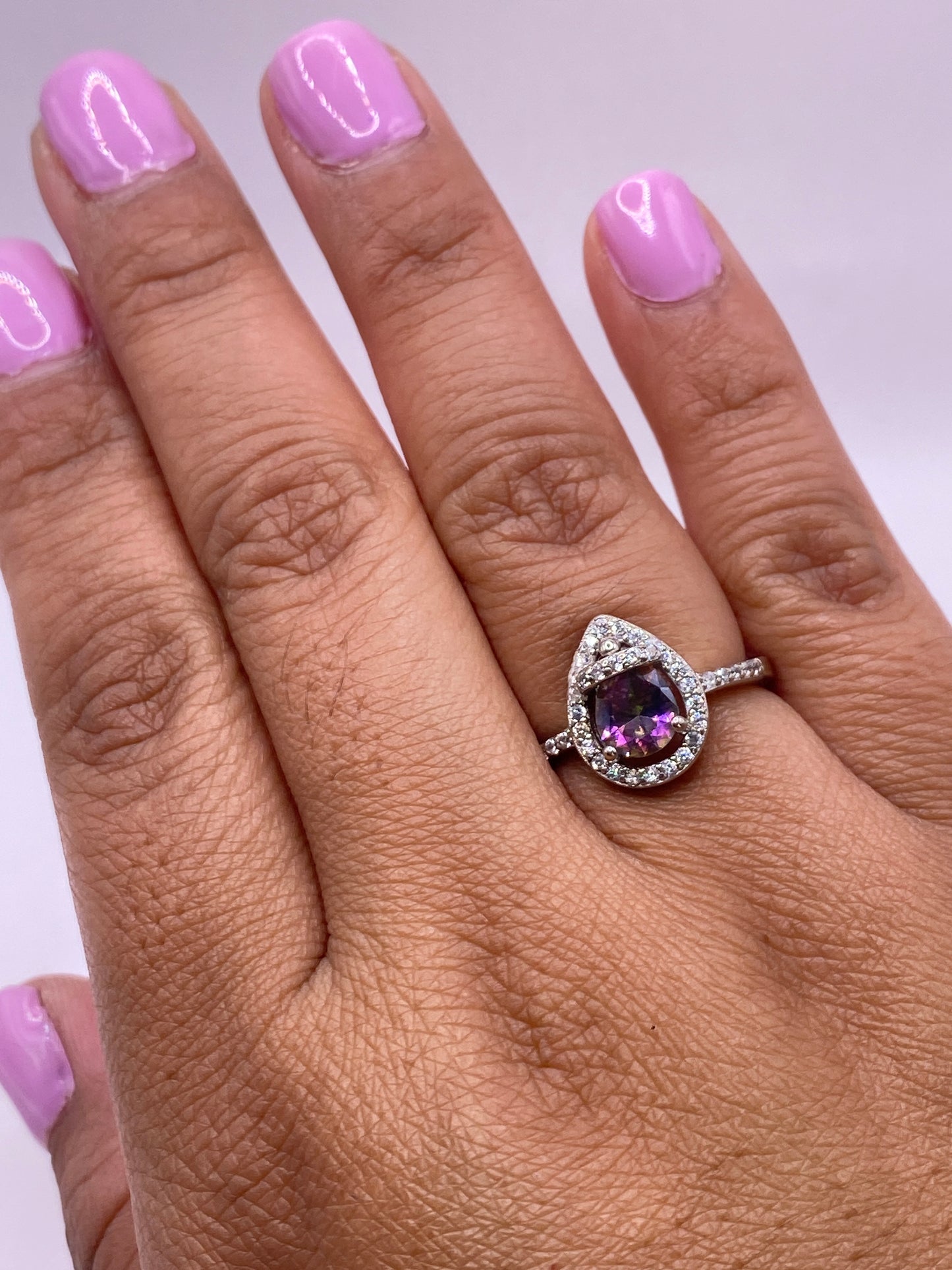 Anillo solitario puesto en mano femenina con manicure rosa pálido, mostrando el brillo de la circonia