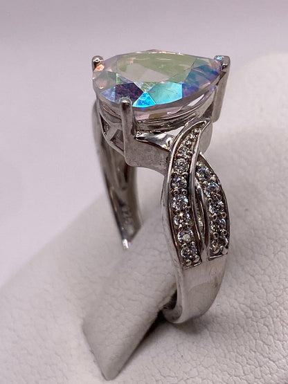 Anillo en mano, circonia gota capturando luz en colores arcoíris
