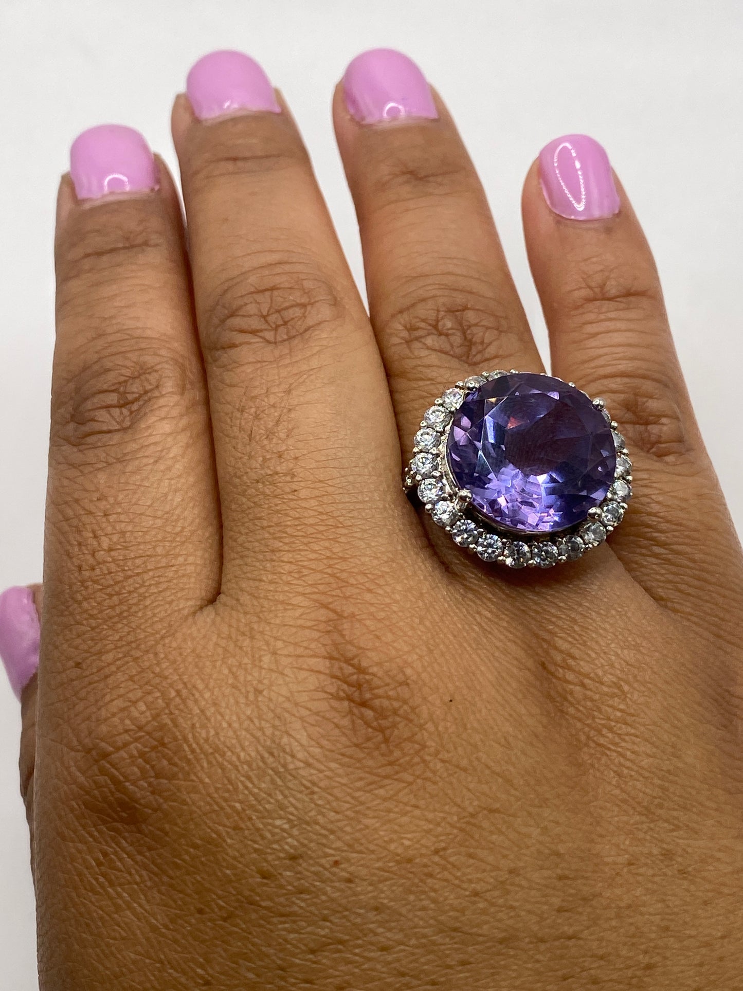 Anillo solitario en dedo con circonia morada brillante, marcando el sello .925