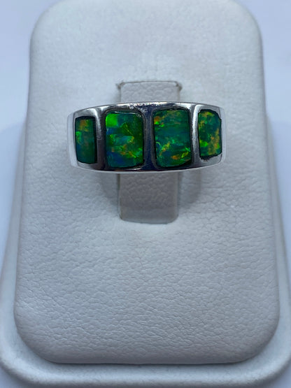 Anillo de plata .925 con ópalo de fuego verde en la mano, mostrando el juego de colores natural