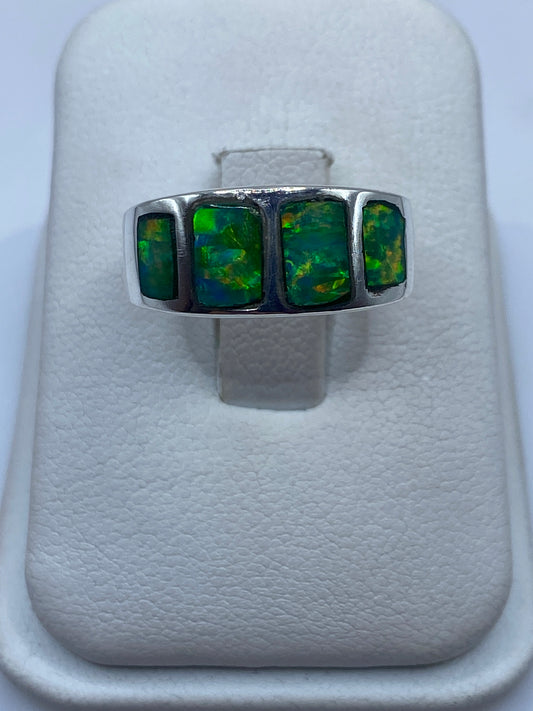 Anillo de plata .925 con ópalo de fuego verde en la mano, mostrando el juego de colores natural