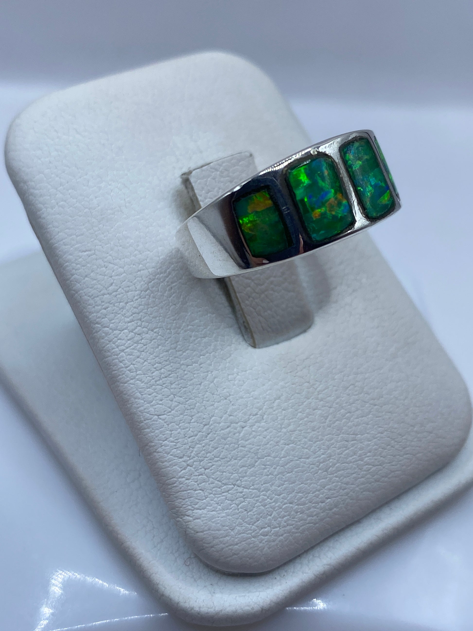 Vista frontal del anillo minimalista con ópalo de fuego verde y bandas laterales de plata