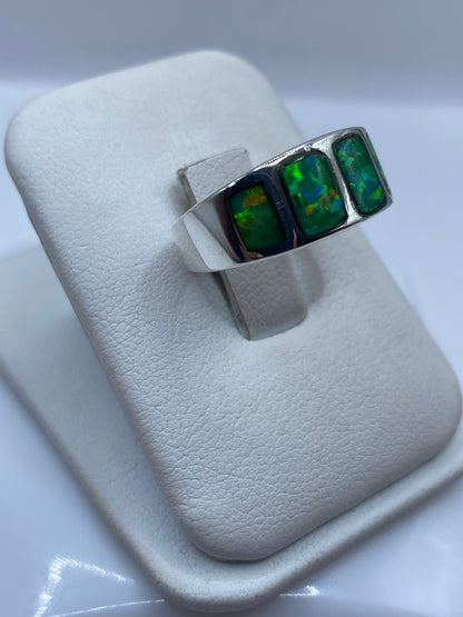Vista frontal del anillo minimalista con ópalo de fuego verde y bandas laterales de plata
