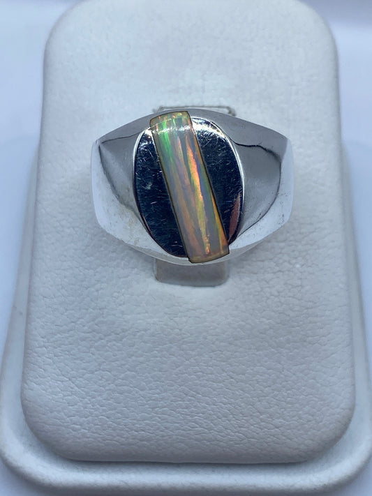 Anillo de plata con ópalo de fuego multicolor mostrando destellos naranjas y verdes