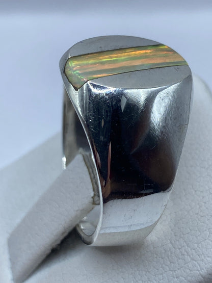 Anillo de ópalo de fuego puesto en mano, luz natural mostrando reflejos verdes, anaranjados y rojos