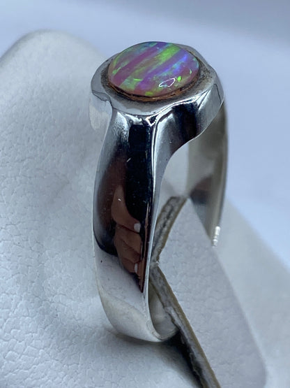 Detalle del ópalo de fuego rosa con reflejos verde y púrpura en la mano