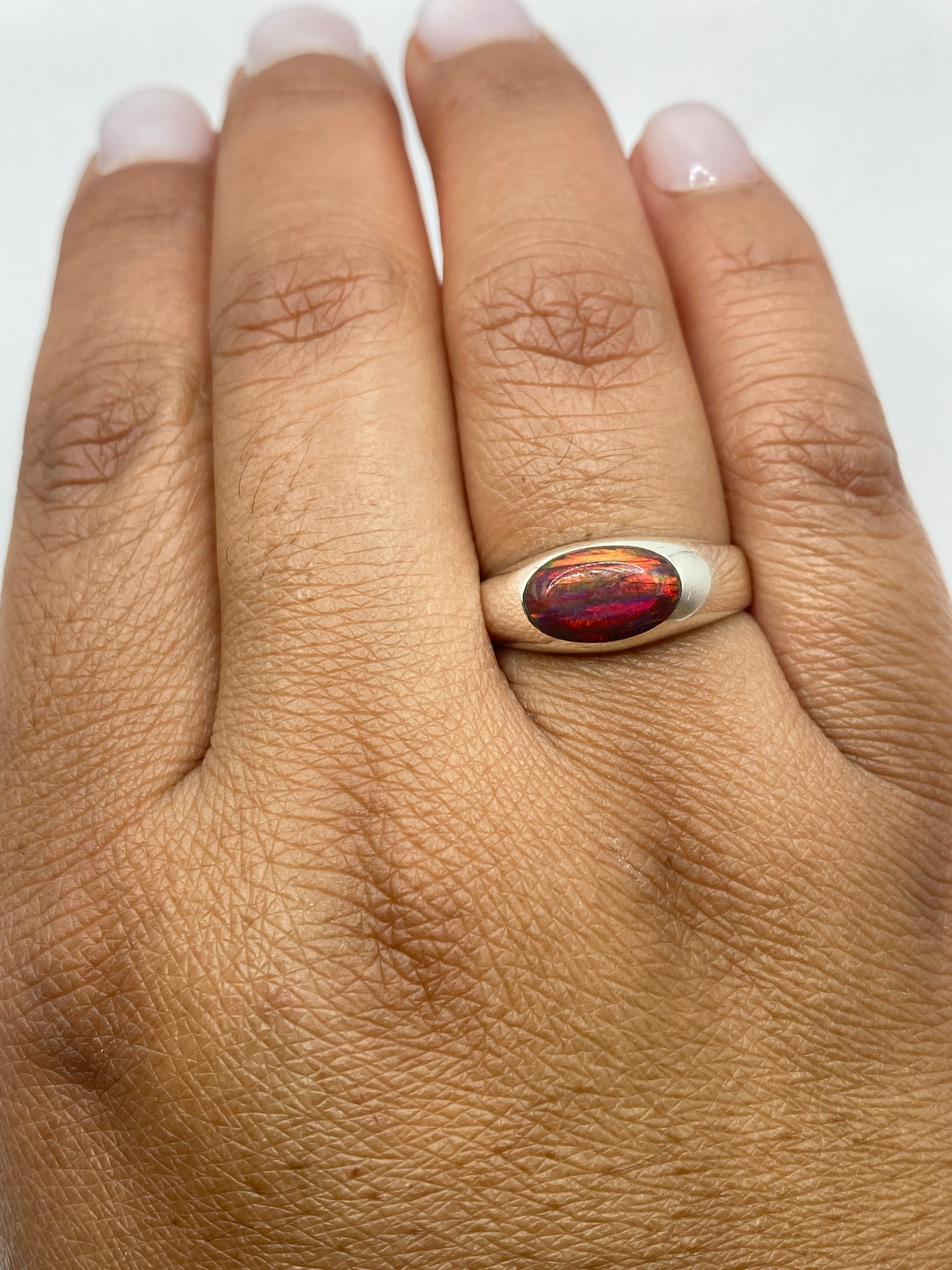 Anillo ópalo de fuego en la mano de una mujer, mostrando la gema desde arriba