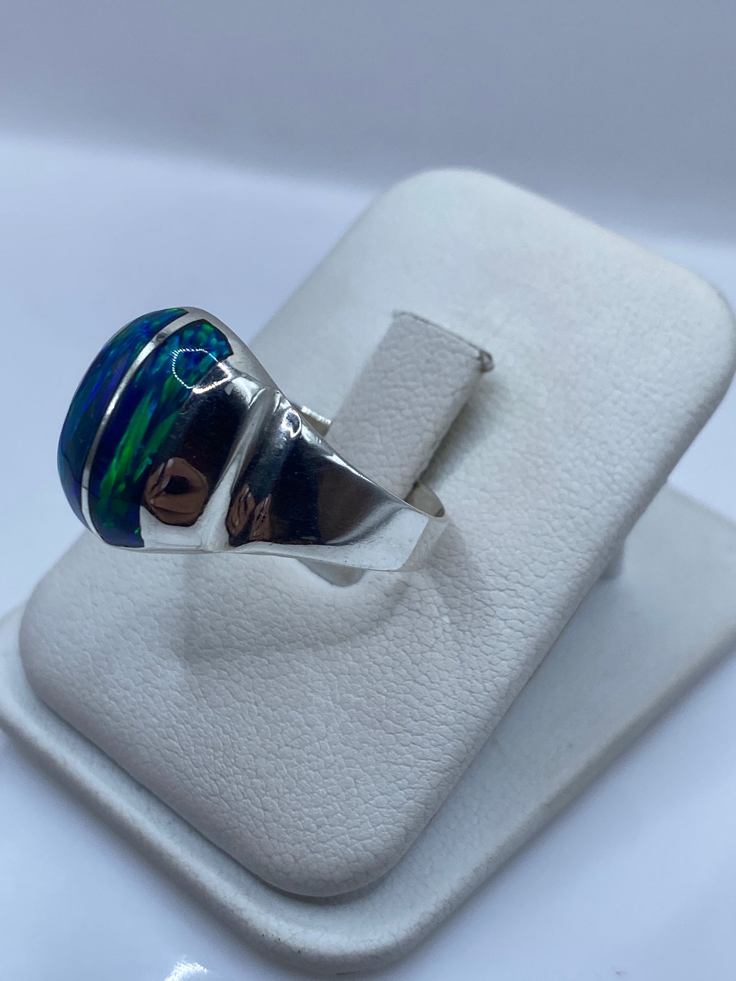 Detalle frontal del ópalo de fuego con juego de color azul en anillo de plata pura