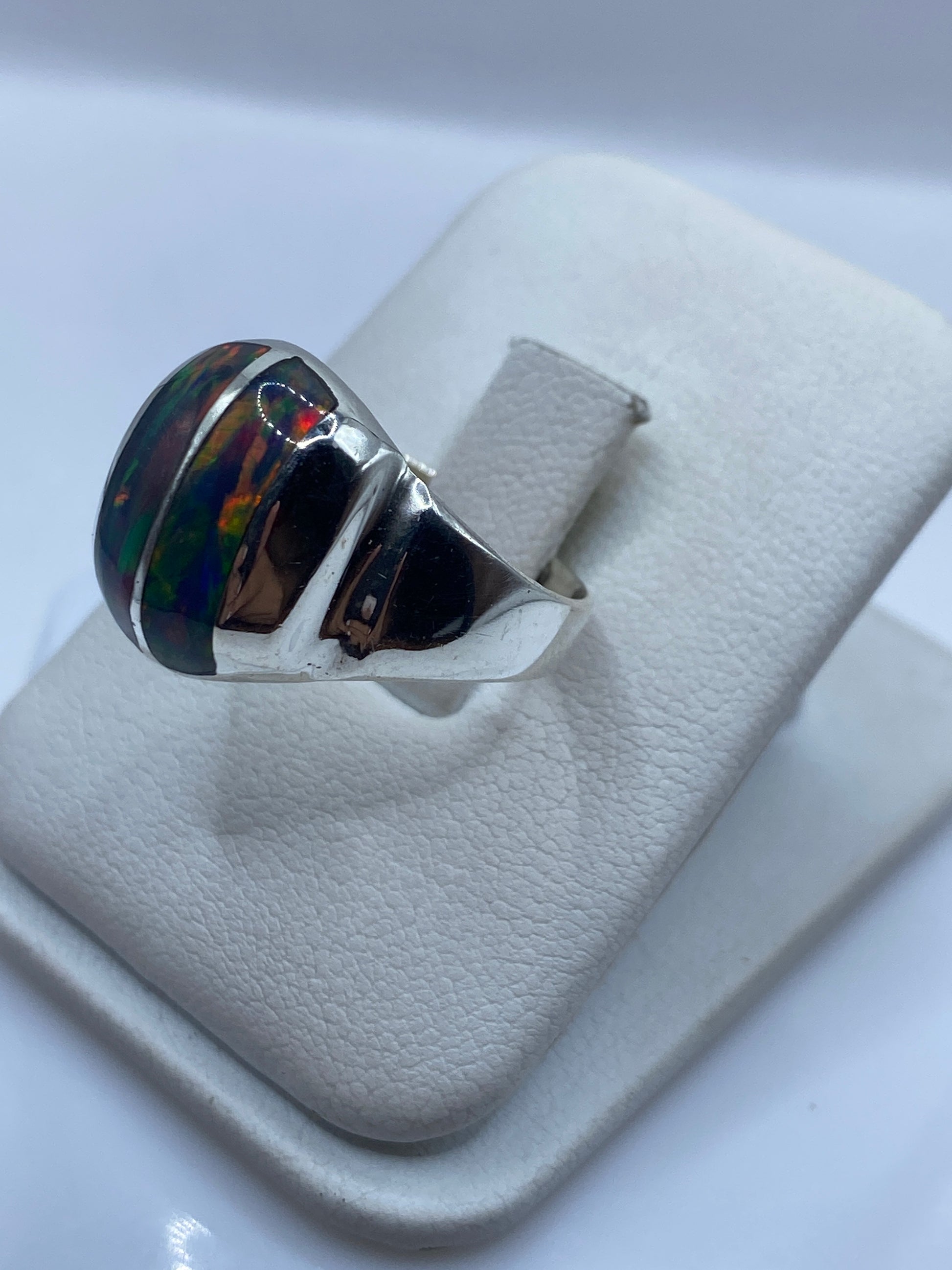 Detalle lateral del anillo mostrando el juego de colores rojo, azul y verde del ópalo de fuego