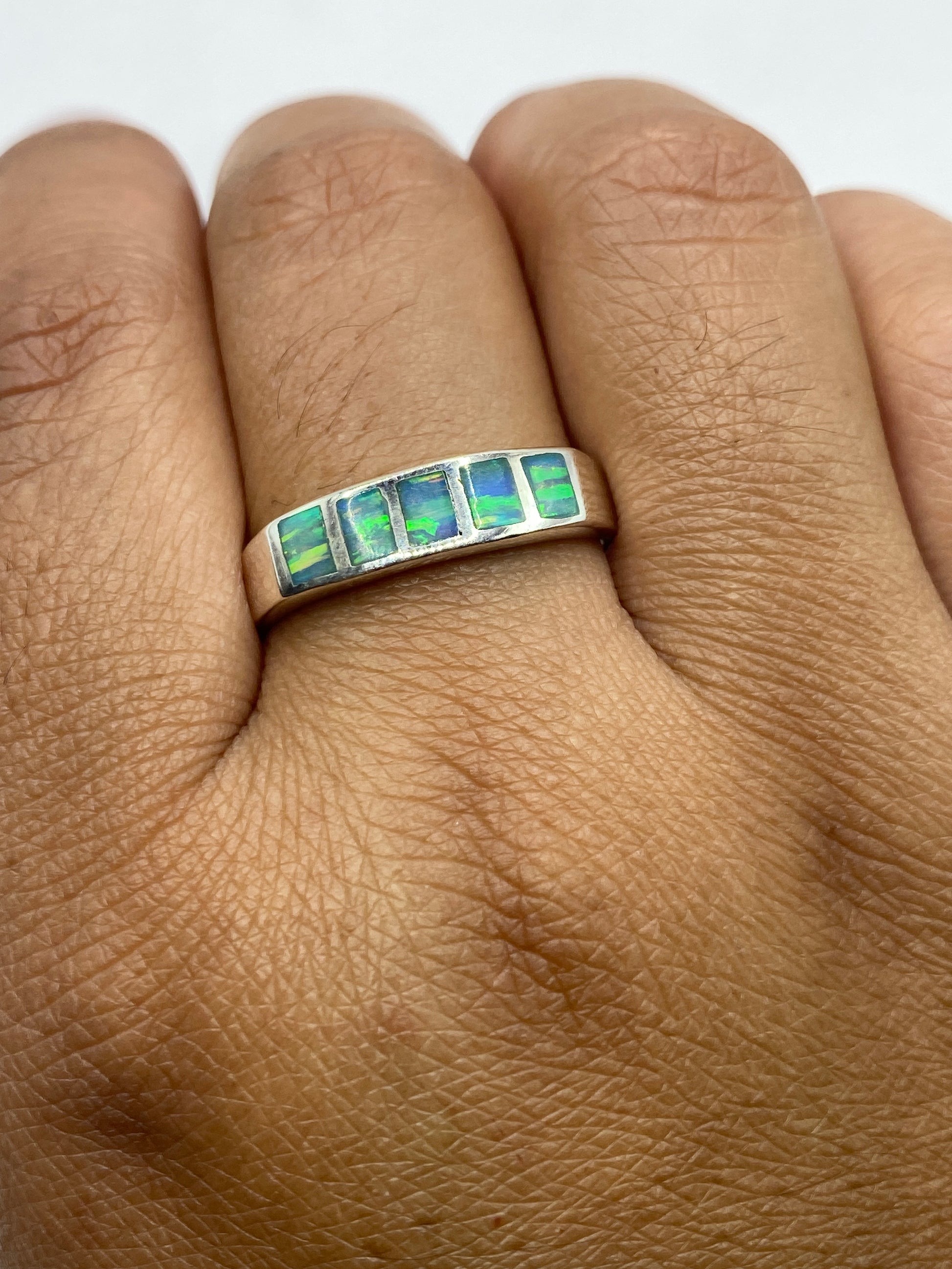Anillo ópalo azul cielo sobre fondo gris, mostrando la banda sólida de plata .950