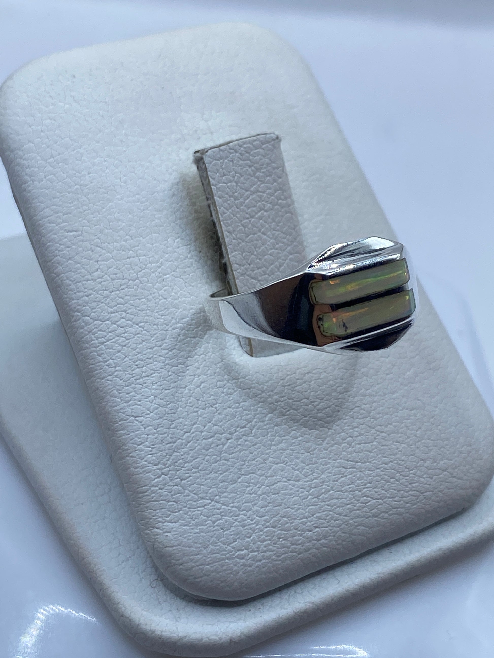 Anillo minimalista en plata .950 con ópalo de fuego puesto en dedo, detalle de los colores verdes y dorados