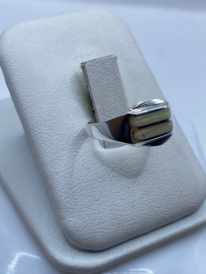 Anillo minimalista en plata .950 con ópalo de fuego puesto en dedo, detalle de los colores verdes y dorados