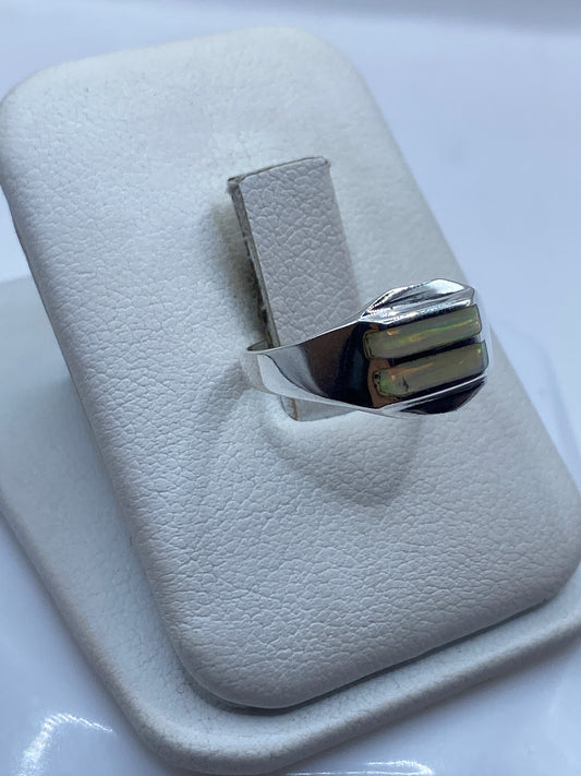 Anillo minimalista en plata .950 con ópalo de fuego puesto en dedo, detalle de los colores verdes y dorados