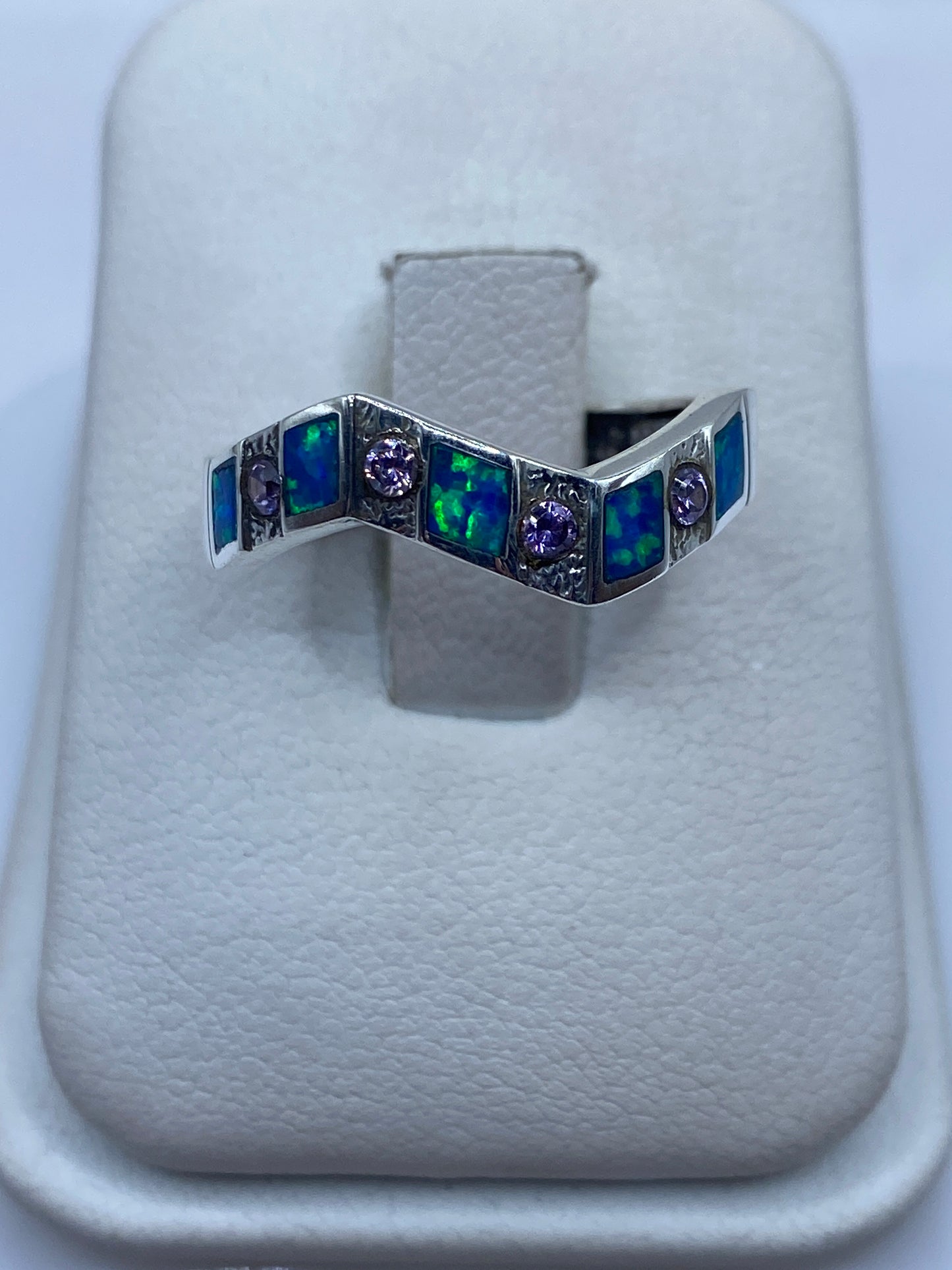 Anillo de plata .950 con ópalo de fuego azul en diseño geométrico, vista frontal sobre almohadilla blanca